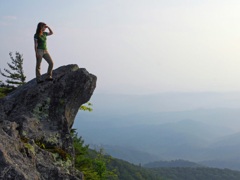 A visitor stands atop the rock overlooking the valley below at The Blowing Rock attraction.
